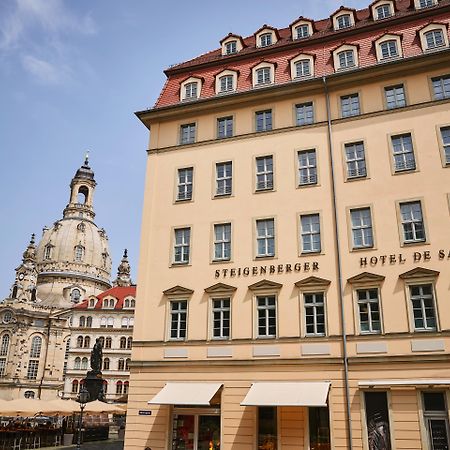 Steigenberger Hotel De Saxe Dresden Exterior photo The photo shows a building in a European city, likely Dresden, Germany. On the left, there is a prominent architectural structure, possibly a church or historical landmark, showcasing classic design elements like a dome and ornate details. To the rig