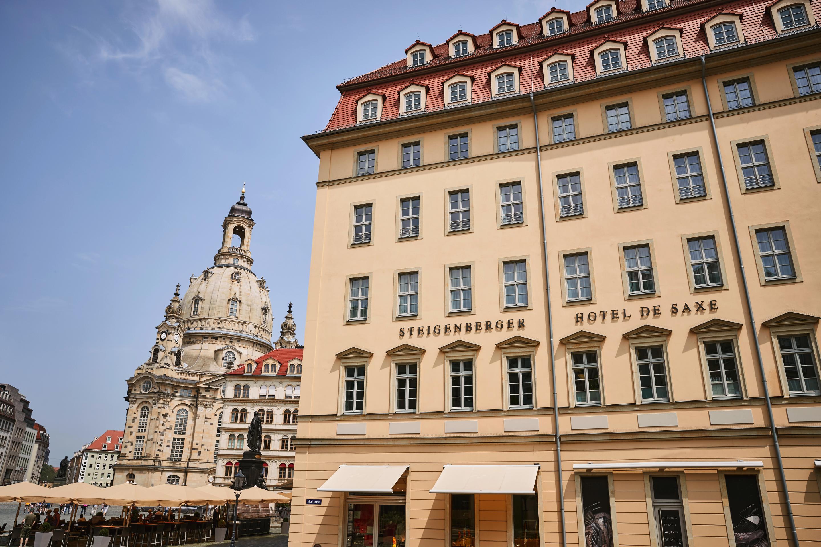 Steigenberger Hotel De Saxe Dresden Exterior photo The photo shows a building in a European city, likely Dresden, Germany. On the left, there is a prominent architectural structure, possibly a church or historical landmark, showcasing classic design elements like a dome and ornate details. To the rig